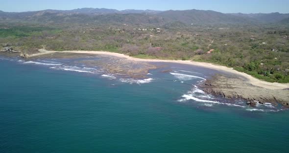 Aerial drone view of the beach, rocks and tide pools in Playa Palada, Guiones, Nosara, Costa Rica.