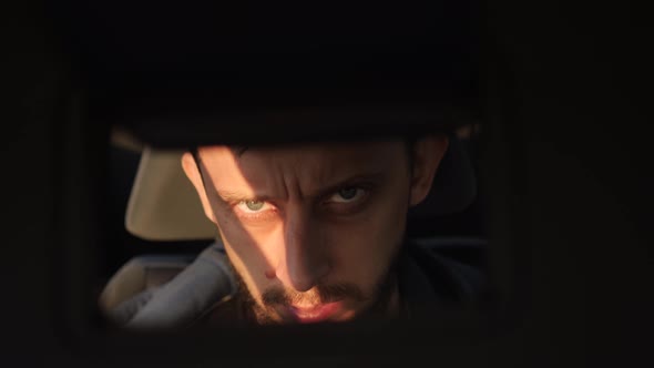 Man Looks at Himself in a Mirror While Sitting in a Car