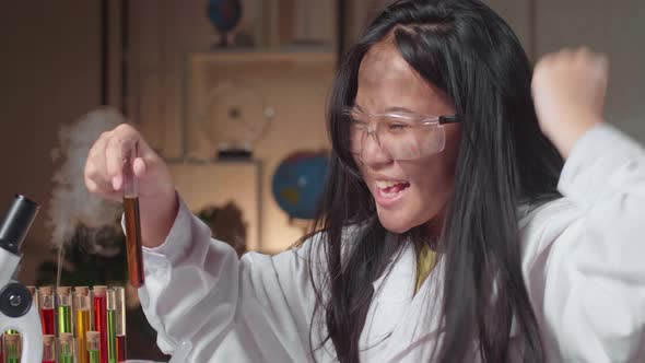 Excited Young Asian Scientist Girl With Dirty Face Mixes Chemicals In Test Tube