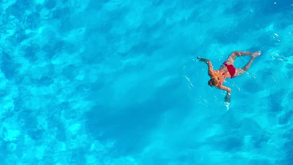 View From the Top As a Woman in Red Swimsuit Swims in the Pool