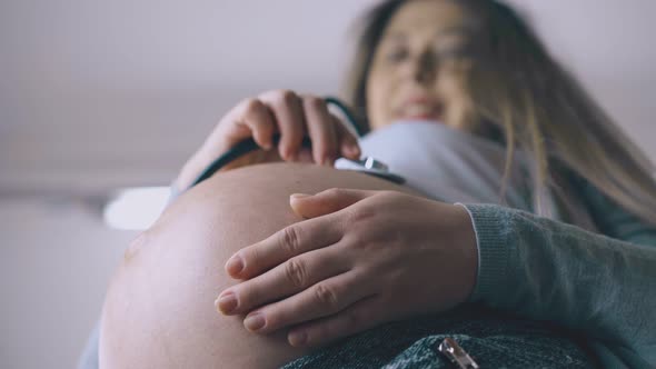 Pregnant Lady Touches Baby Bump with Stethoscope Closeup