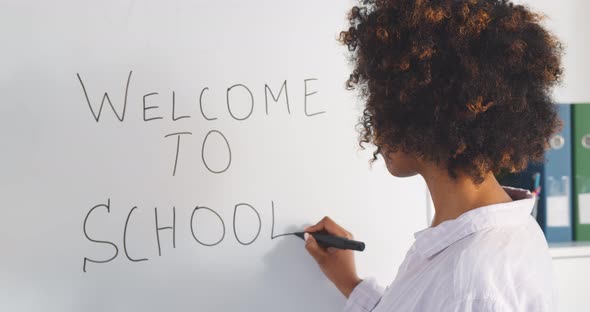 African Young Female Teacher Writing Welcome to School on White Board in Classroom