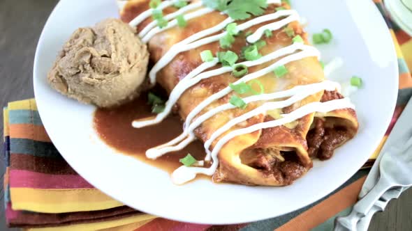 Close up of dinner plate with Chicken enchiladas garnished with green onions and sour cream.