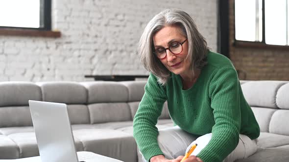 Mature Senior Woman Is Using a Laptop at Home