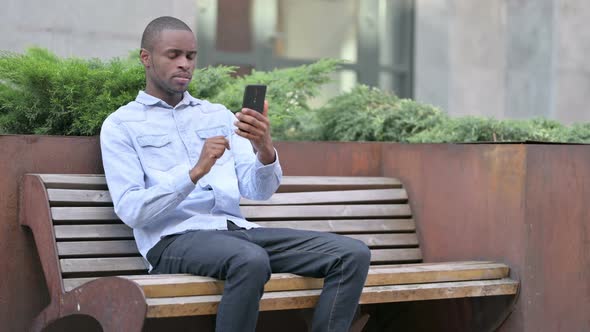 Upset African Man Having Loss on Smartphone Outdoor 