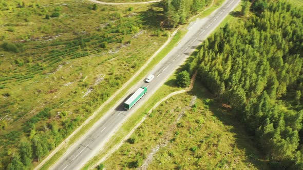 Aerial View Of Highway Road Through Field And Summer Green Forest Landscape
