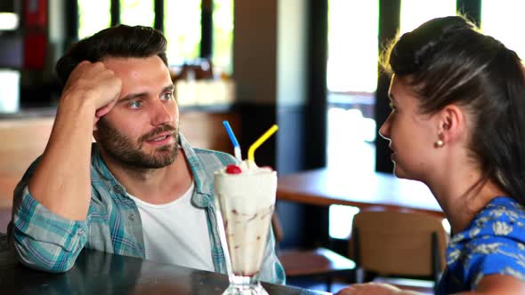Happy couple interacting while having milkshake