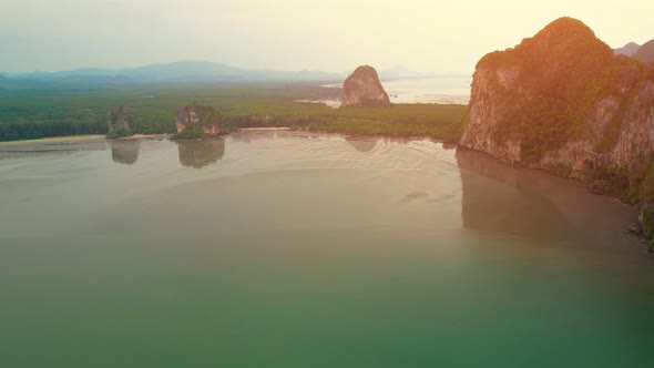 A view from a drone flying over rocky mountains and sandy beaches at low tide