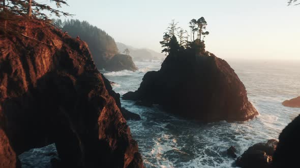 Drone Flying at Narrow Ocean Cliffs with Waves Crashing Over Shore Rocks Below