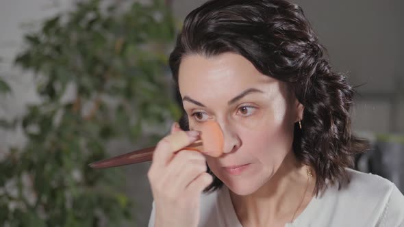 Applying the Morning's Makeup. The Brunette Creates a Face Drawing for Herself