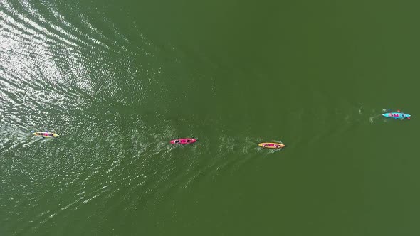 Aerial Top Down of Colorful Kayaks with Paddlers on River Surface Reflecting Sun