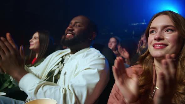 Smiling People Having Fun in Cinema. Cheerful Group Applauding in Dark Hall.