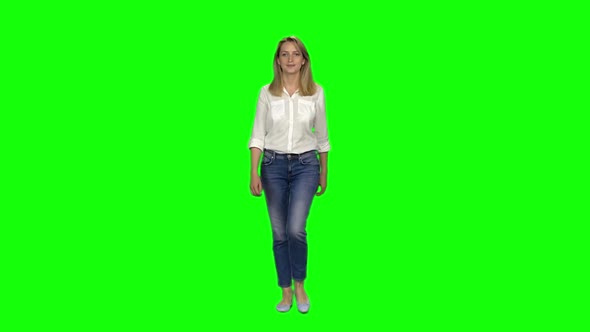 Blonde Woman Is Calmly Walking and Smiling on Green Screen. Chroma Key. Front View. Slow Motion