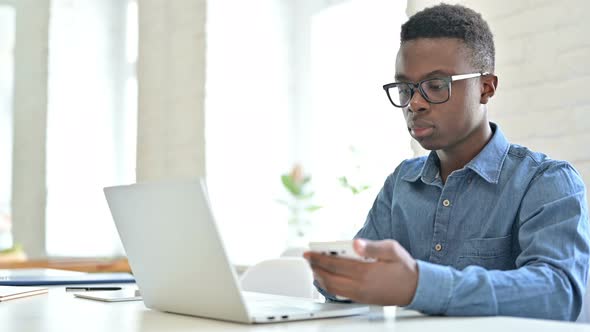 Young African Man using Laptop and Smartphone