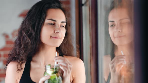 Happy Adorable Young Curly Brunette Girl Drinking Refreshing Cocktail Looking Out Window