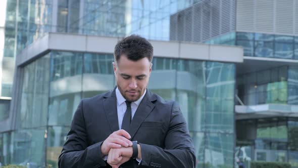 Businessman Using Smartwatch While Walking Toward Office