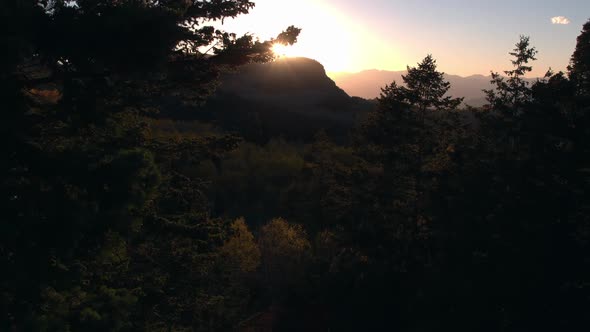 Aerial view of the sun setting on a beautiful mountainside in the fall.