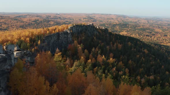 Aerial View of a Cliff Surrounded By a Colorful Autumn Forest at Sunset