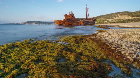 Time lapse of golden hour in the morning of ship wreck Dimitrios with waves flowing over mossy groun