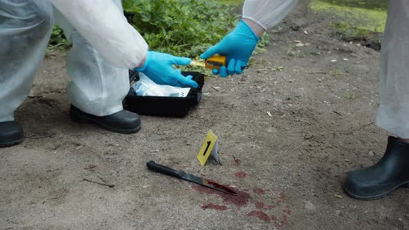 Criminalists Discovering Knife at Crime Scene Measuring Crime Scene Closeup Taking Evidence From