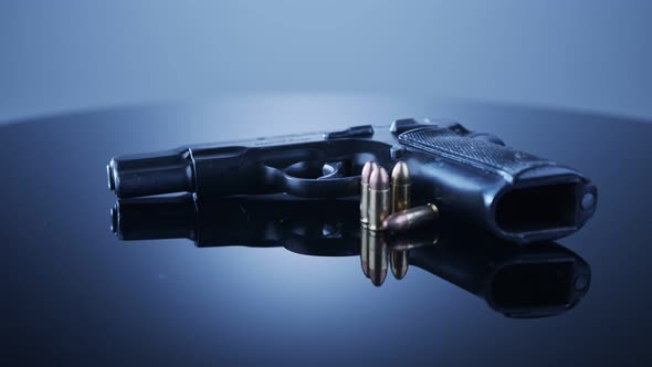 Gun Control. 9mm handgun with bullets rotating on a reflective surface