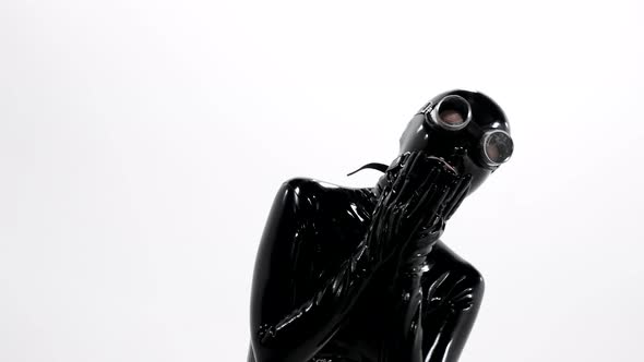 Closeup of a Woman Dressed in a Tight Black Latex Suit for a BDSM Roleplaying Game She Poses Against