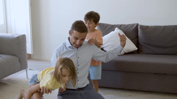 Exited Caucasian Man Playing with Children and Showing Strength