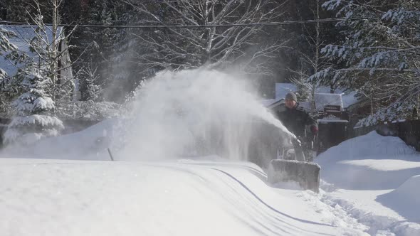 Man cleans snow on footpaths with snowblower.