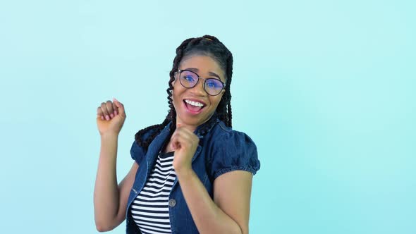 Cute Cheerful Young African American Girl in Blue Clothes Poses and Dances in a Photo Studio
