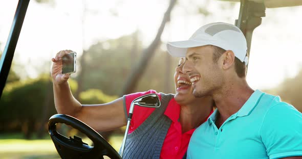 Two happy golfers taking a selfie in golf buggy