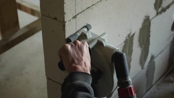 men's hands with an electric tool to make a groove in the foam block for routing electricity