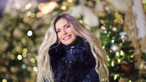 Portrait of Laughing Pretty Woman Posing Surrounded By Snowflakes at Christmas Tree Lights Bokeh