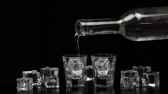 Pouring Up Two Shots of Vodka From a Bottle Into Glass. Black Background