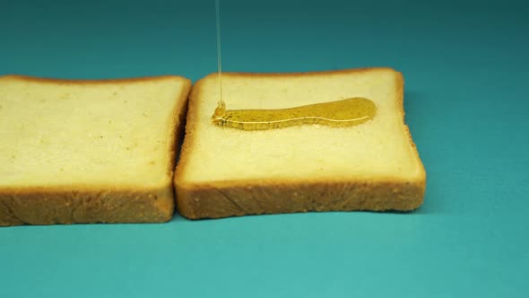 Liquid Honey Pouring on a Piece Bread