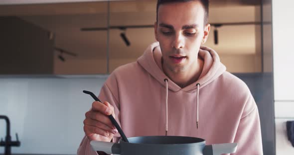 Young Caucasian Man Cooking and Trying Soup at Home Taste Good