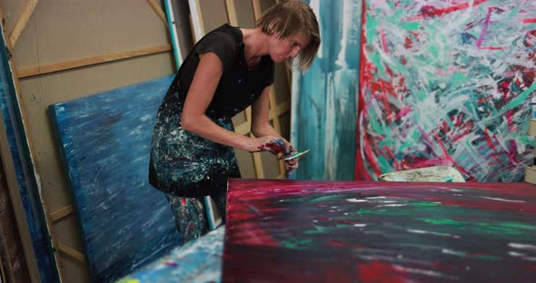 Senior woman painting inside her atelier studio at home