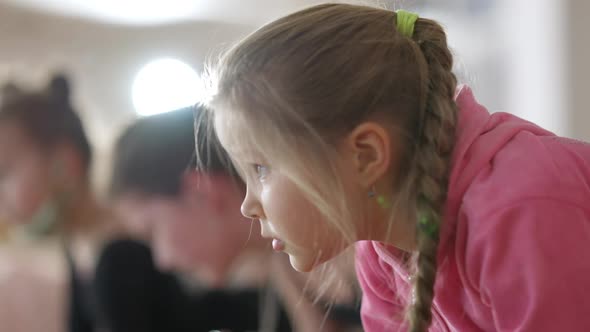 Closeup Face of Persistent Little Girl with Pigtails Standing in Plank Position in Dance Studio