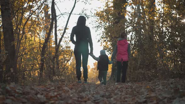 Mother and Two Children Walking in the Park and Enjoying the Beautiful Autumn Nature. Happy Family