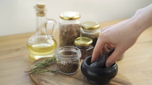 Woman's Hand Mixes and Crushes Coriander Seeds By Granite Mortar with Pestle in Slow Motion