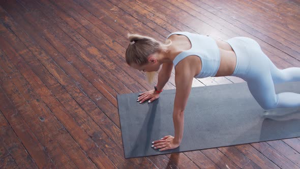 Young and sporty girl in sportswear is doing exercises at home.