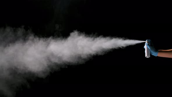 A Man's Hand in a Protective Glove Sprays a Disinfecting Aerosol Spray on a Black Background