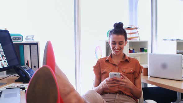 Female executive using mobile phone at her desk