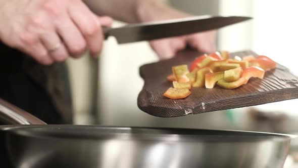 professional chef puts slices of vegetables from the cutting Board into the pan