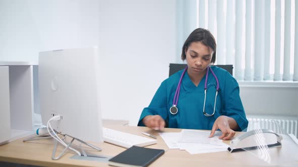 Serious Female Doctor Sits at Workplace in Modern Hospital and Works with Patients Survey Documents