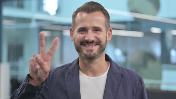 Positive Middle Aged Businessman Showing Victory Sign