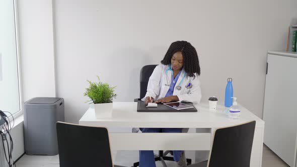 Smiling African American doctor writing in notebook