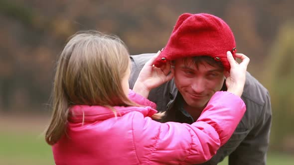 Girl putting her cap on dad's head