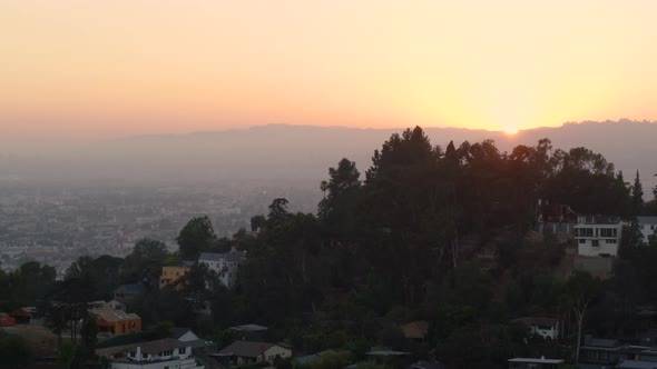 Aerial of houses on mountain top overlooking cityscape at sunset