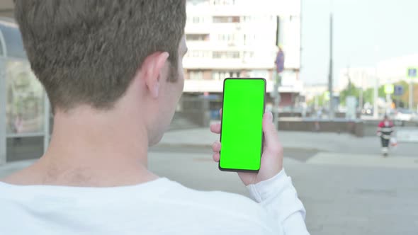 Young Man Using Smartphone with Green Screen Outdoor