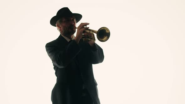 Senior Bearded Male Musician Plays Musical Trumpet in Studio on White Background Double Exposure